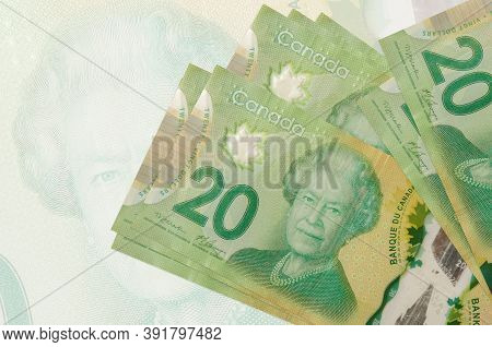 20 Canadian Dollars Bills Lies In Stack On Background Of Big Semi-transparent Banknote. Abstract Pre