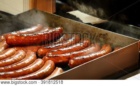 Many Grilled Sausages Lie Next To Each Other On A Grill.