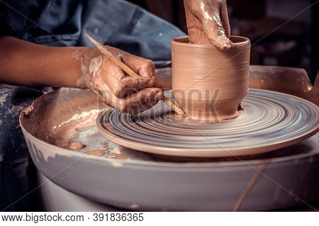 Master-ceramist Creates A Clay Pot On A Potters Wheel. Hands Of Potter Close Up. Ancient Craft And P