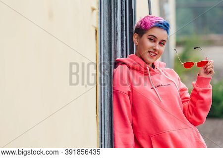 Portrait Of A Young Girl With Short Colorful Hair And Nose Piercing Satanding Near The Wall With Woo