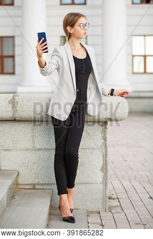 Full length portrait of a young beautiful girl in a gray jacket and black jeans