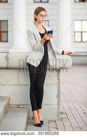 Full length portrait of a young beautiful girl in a gray jacket and black jeans