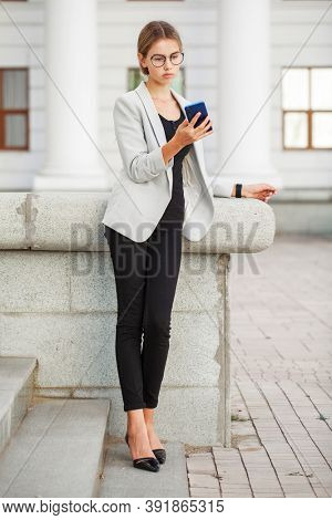 Full length portrait of a young beautiful girl in a gray jacket and black jeans