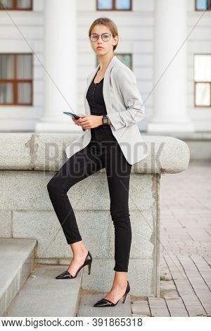 Full length portrait of a young beautiful girl in a gray jacket and black jeans