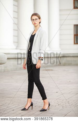 Full length portrait of a young beautiful girl in a gray jacket and black jeans