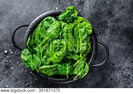 Young Raw Spinach In A Colander. Black Background. Top View