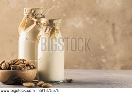 Vegan Almod Milk And Cream In Bottles, Closeup, Brown Background. Non Dairy Alternative Milk. Health