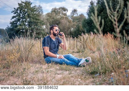 Modern Man Enjoying An Electronic Smoke Device In The Forest. Non-tobacco Smoking.