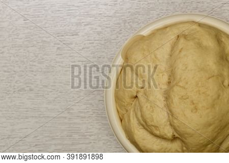 Fragment Of The Bowl With A Raised Fermented Yeast Dough. On The Table.