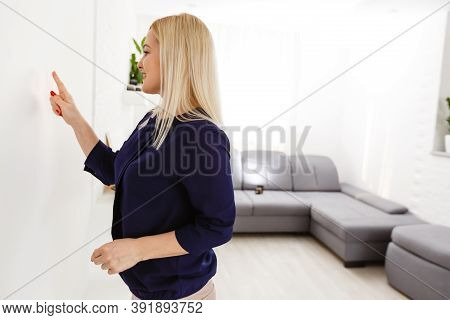 Middle Aged Woman Pushing Button Of Intercom