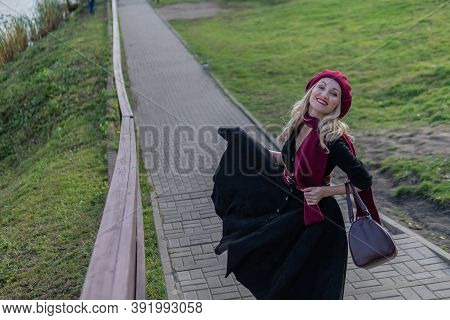 A Beautiful Lady Is Walking Up The Stairs And In A Burgundy Palette And Biret, Looking At The Camera