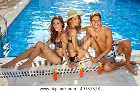 Friends Sunbathing At The Edge Of A Pool
