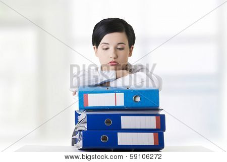 Sad woman with ringbinders sitting at the desk. Tired and exhousted business woman. 