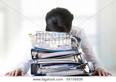 Sad woman with ringbinders sitting at the desk. Tired and exhousted business woman.