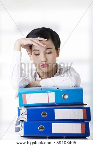 Sad woman with ringbinders sitting at the desk. Tired and exhousted business woman.