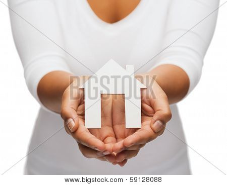 real estate concept - closeup of woman hands holding paper house