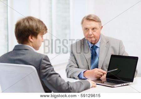 business, advertisement, technology and office concept - older man and young man with laptop computer in office