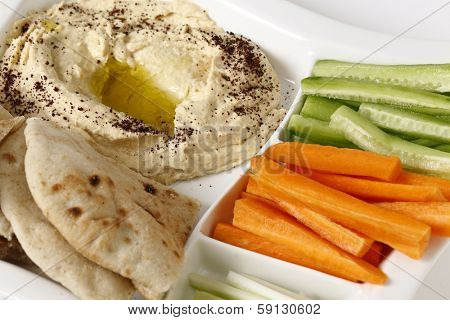 A dip tray with hummus, bread, carrot sticks, celery and cucumber.
