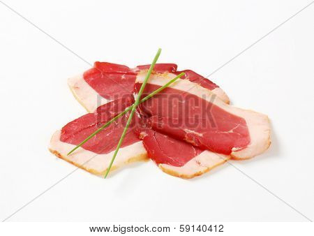 four thin slices of duck breast decorated with chive
