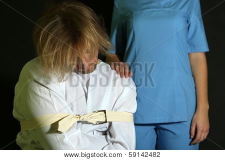 Mentally ill man in strait-jacket on black background