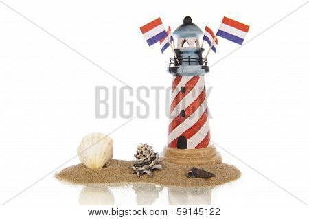 Lighthouse With Flags And Assorted Shells In Sand