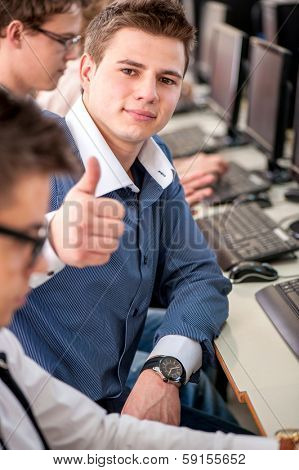 Positive highschool boy in schoolroom showing thumb up