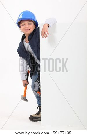 Little girl dressed as builder stood with poster