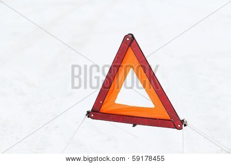 transportation and winter concept - closeup of warning triangle on snow