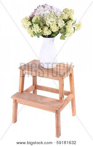 Vase with flowers on small wooden ladder, isolated on white