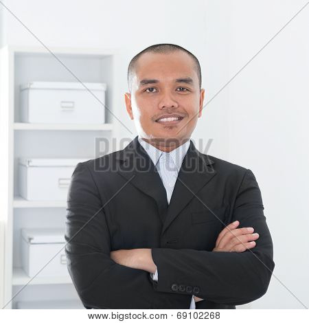 Portrait of 30s Asian Muslim business man smiling, real modern office background.
