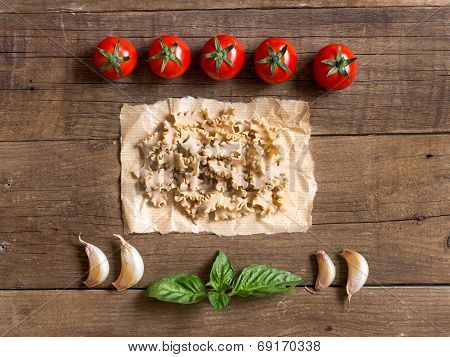 Pasta, Tomatoes, Garlic And Basil On Wooden Background