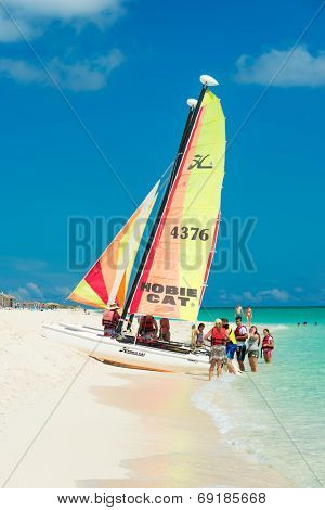 CAYO SANTA MARIA, CUBA - JULY 16, 2014 : Tourists getting ready to sail on a colorful catamaran on a sunny day at the beach