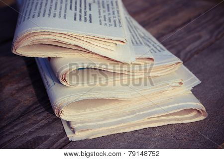 Newspapers on old wood background. Toned image.