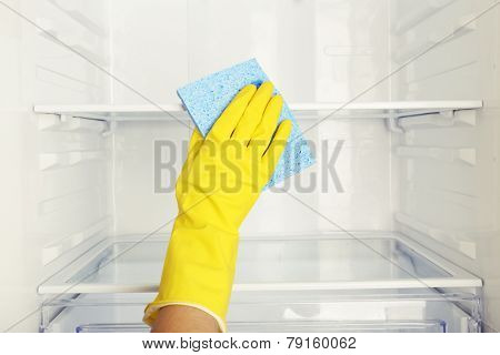 Woman's hand washing refrigerator with duster