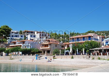 ALONISSOS, GREECE - SEPTEMBER 23, 2012: People sit on the shingle beach at Rousoum on the Greek island of Alonissos. Rousoum was once the centre of the islands wine exporting trade.