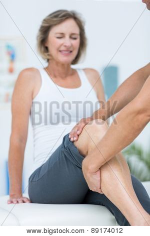 Doctor examining his patients knee in medical office