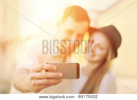 Touristic couple shooting on the modile phone at the city streets under sunlight.