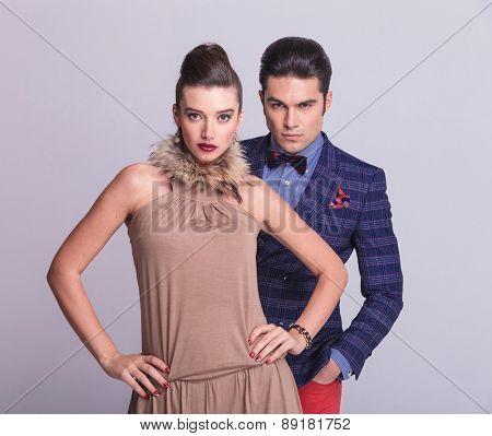 Portrait of a young fashion couple posing together on greu studio background.
