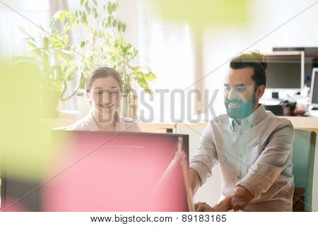 business, startup and people concept - happy creative team networking with computer in office, shot through window glass