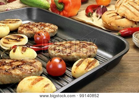 Homemade Pan-fried Burgers In Grill-pan On Rustic Dinning Table. Still-life