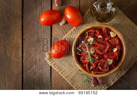 Sun-dried tomatoes with herbs and garlic in wooden bowl