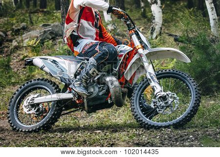 Enduro racer is riding through the woods