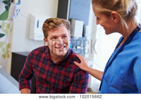 Male Patient Being Reassured By Nurse In Hospital Room