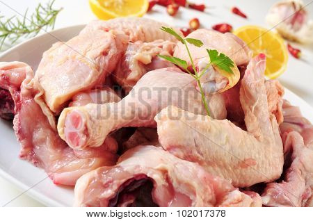 closeup of a plate with the different pieces of a butchered chicken on the countertop of a kitchen