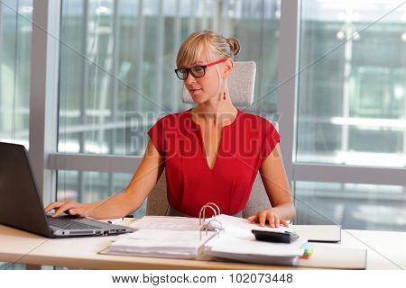 caucasian business woman in eyeglasses working on laptop in her office