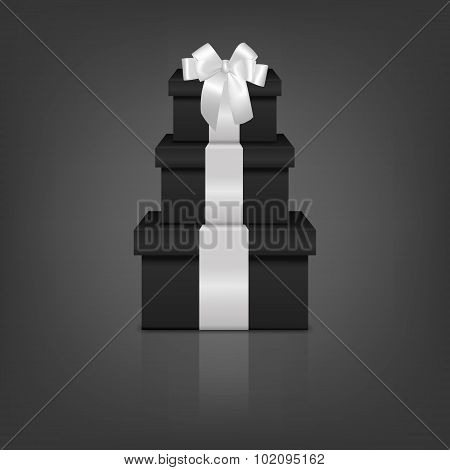 Stack of three realistic black gift boxes with white ribbon and bow