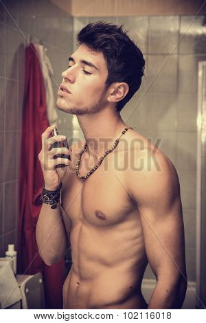 Handsome young man in bathroom, spraying cologne or perfume