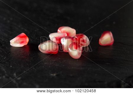 Small Heap Of Pomegranate Seeds On Black Slate Surface