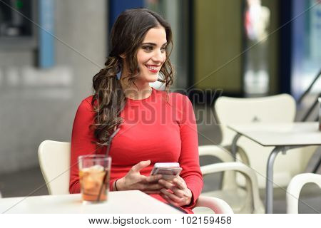 Young Woman Looking At Her Smartphone Sitting In A Cafe