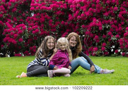 Mother With Daughters Sitting On Grass
